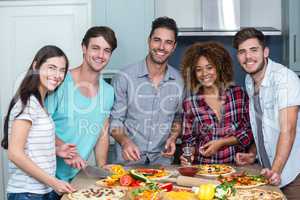 Portrait of happy multi-ethnic friends preparing pizza at home