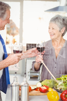 Happy senior man offering red wine to wife