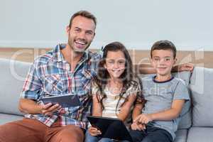 Father and siblings using digital tablet