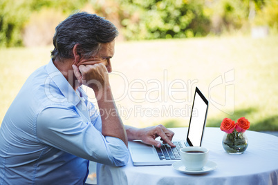 Casual businessman using laptop and having coffee