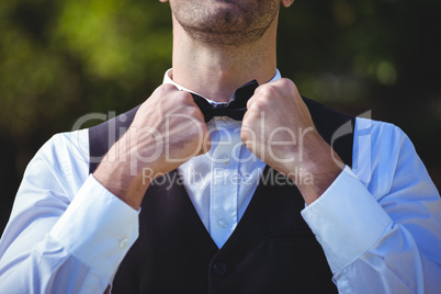 Handsome waiter reattaching his bow tie