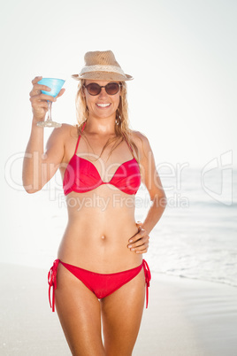 Young woman with a cocktail drink standing on the beach