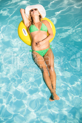 Beautiful woman in green bikini floating on inflatable tube in s