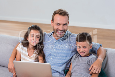 Father sitting on sofa with son and daughter