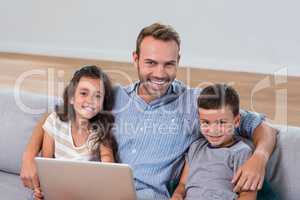 Father sitting on sofa with son and daughter