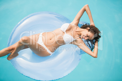 Beautiful woman relaxing on swim ring at swimming pool