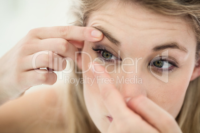 Close-up of young woman applying contact lens