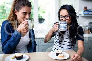 Young female friends drinking coffee at table