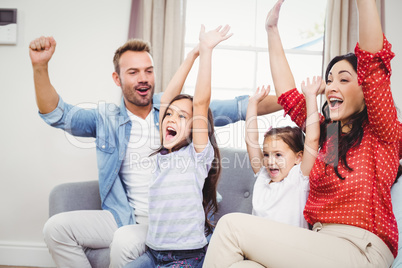 Family cheering while sitting on sofa