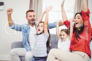 Family cheering while sitting on sofa