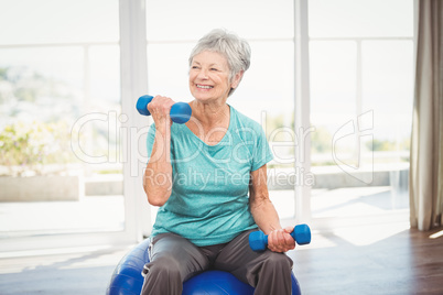 Smiling senior woman holding dumbbell