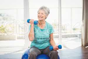 Smiling senior woman holding dumbbell