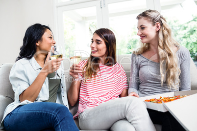 Female friends with pizza drinking wine at home