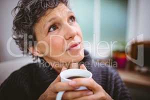 Thoughtful mature woman holding coffee cup