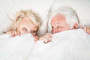 Overhead view of couple hiding in blanket