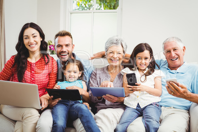 Portrait of happy family holding technologies at home