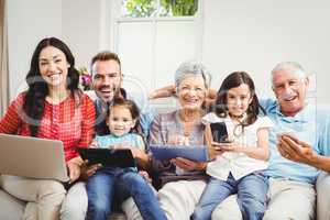 Portrait of happy family holding technologies at home