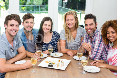 Multi-ethnic friends enjoying wine and sushi on table