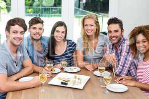 Multi-ethnic friends enjoying wine and sushi on table