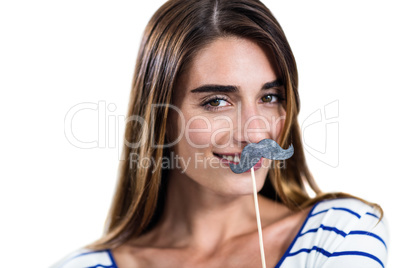 Portrait of smiling woman holding artificial mustache