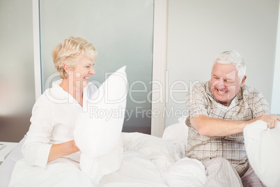 Senior couple having pillow fight in bed