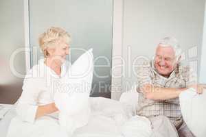 Senior couple having pillow fight in bed