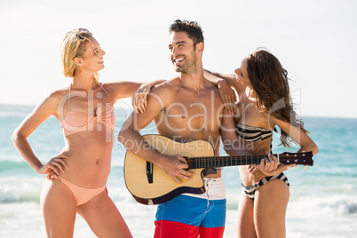 Happy friends posing and playing guitar on the beach