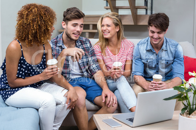 Young friends with drinks sitting on sofa