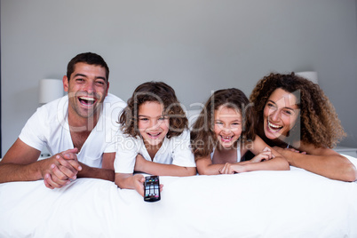 Portrait of happy family lying on bed