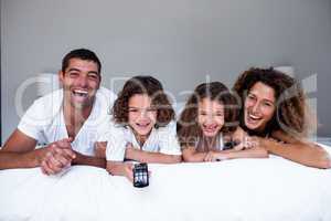 Portrait of happy family lying on bed