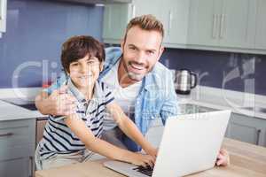 Portrait of smiling father and son using laptop