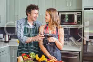 Happy couple toasting wine in kitchen