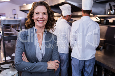 Happy restaurant manager standing with arms crossed in commercia