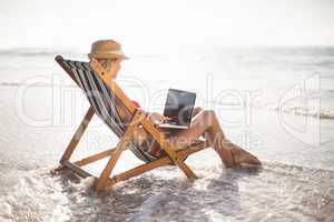 Woman sitting on a armchair and using a laptop