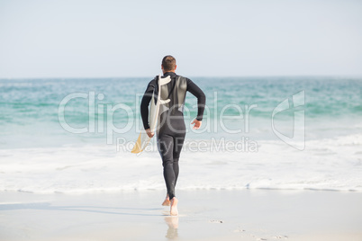 Surfer walking towards sea with a surfboard