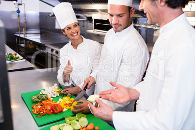 Head chef teaching his colleagues how to slice vegetables