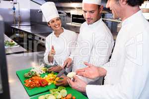Head chef teaching his colleagues how to slice vegetables