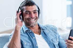 Young man listening to music while using mobile phone