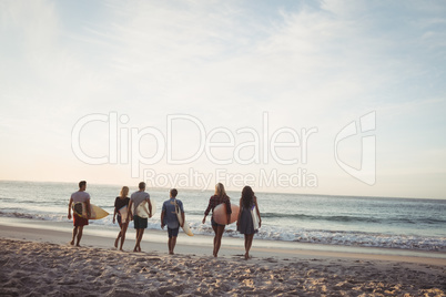 Happy friends walking with surfboards