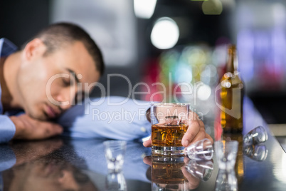 Tired man having a whiskey and sleeping on a counter