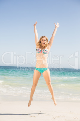 Carefree woman in bikini jumping on the beach