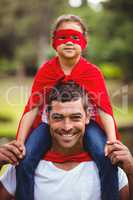 Girl in superhero costume sitting on fathers shoulder