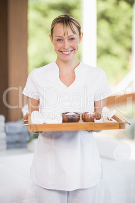 Female masseur holding tray with spa therapy products