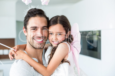 Portrait of cheerful father carrying daughter in fairy costume
