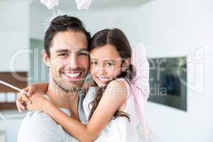 Portrait of cheerful father carrying daughter in fairy costume
