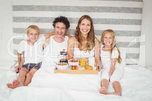 Portrait of smiling family enjoying breakfast on bed