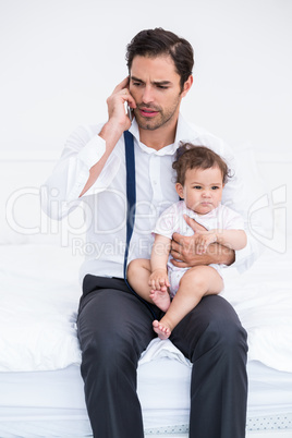 Father talking on mobile phone with baby