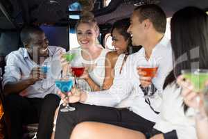 Well dressed people drinking cocktails in a limousine