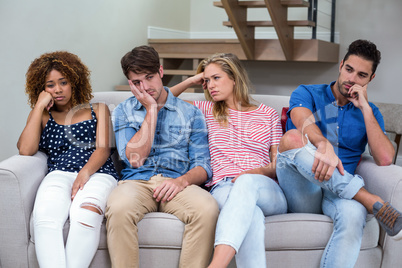 Upset young friends sitting on sofa