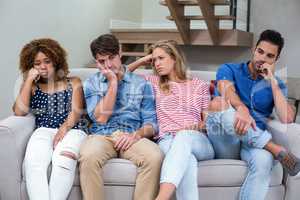 Upset young friends sitting on sofa